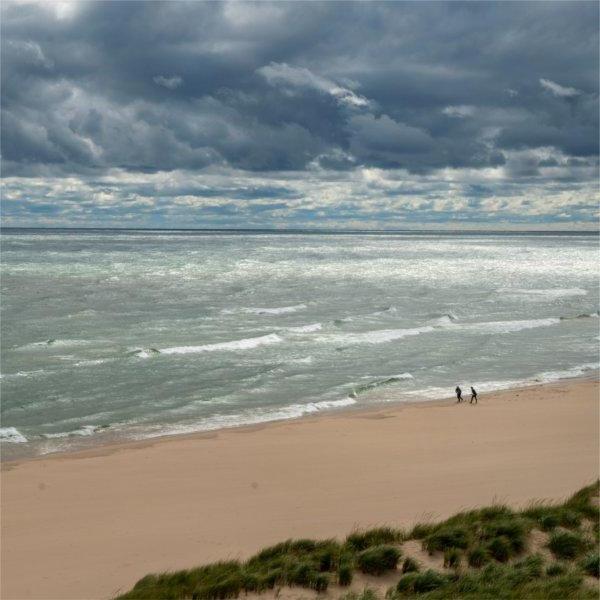 Two people walk the beach along Lake Michigan.